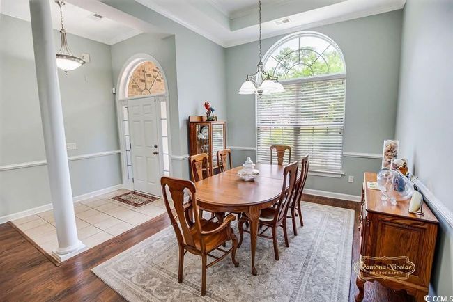 Dining area featuring wood finished floors, healthy amount of natural light, decorative columns, ornamental molding, and a raised ceiling | Image 15