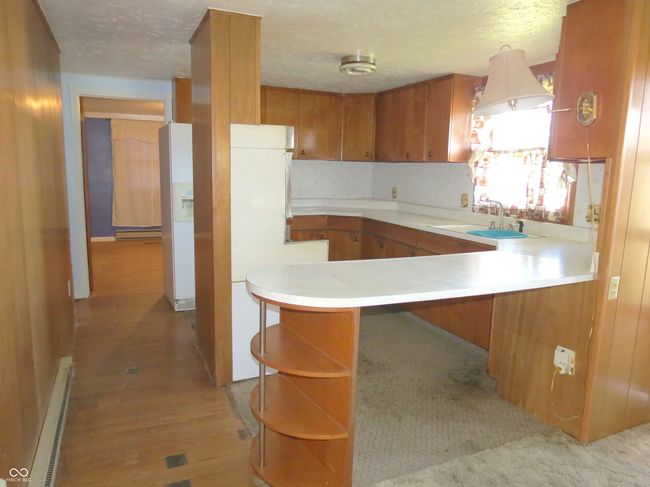 kitchen featuring a sink, baseboard heating, brown cabinetry, and light countertops | Image 7