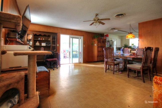 Dining room featuring wooden walls, ceiling fan, light floors, and a textured ceiling | Image 6