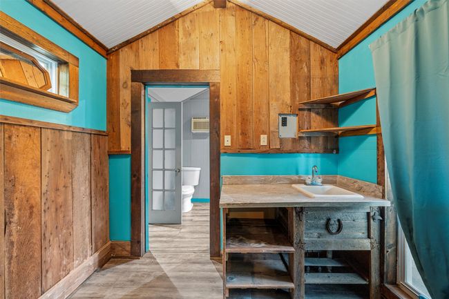 Kitchen featuring wood walls, vaulted ceiling, open shelves, and light wood-style floors | Image 30