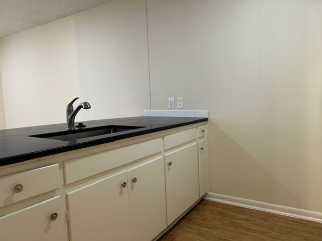 Kitchen with baseboards, a sink, dark countertops, and wood finished floors | Image 4