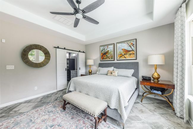 The primary bedroom showcases an upgraded barn door, a stylish focal point that leads to the bathroom. This feature adds a modern touch and seamlessly blends with the room’s contemporary design. | Image 21