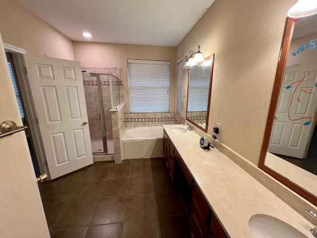 Bathroom featuring a bath, tile patterned floors, a stall shower, and double vanity | Image 10