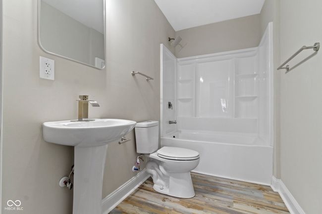 bathroom featuring toilet, wood finished floors, bathtub / shower combination, and baseboards | Image 33