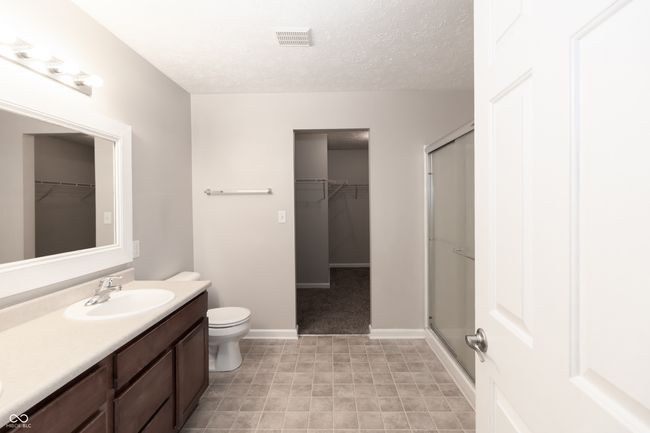 full bath featuring a walk in closet, vanity, a shower stall, and a textured ceiling | Image 16
