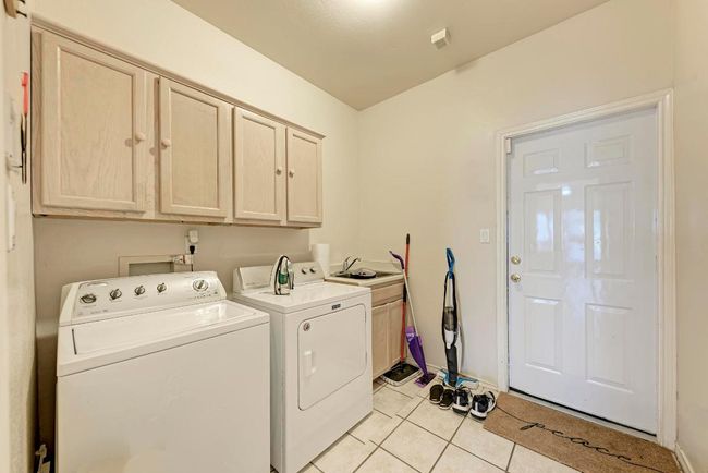 Laundry room featuring cabinet space, washer and dryer, and light tile patterned flooring | Image 29