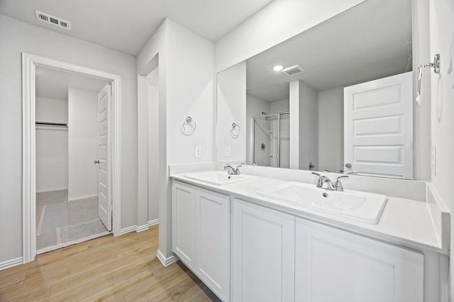 Bathroom featuring double vanity, wood finished floors, and a shower with shower door | Image 12