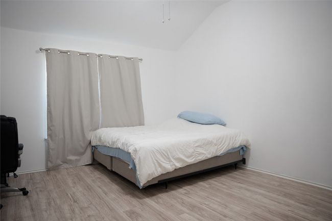 Bedroom with wood finished floors, lofted ceiling, and an office area | Image 14