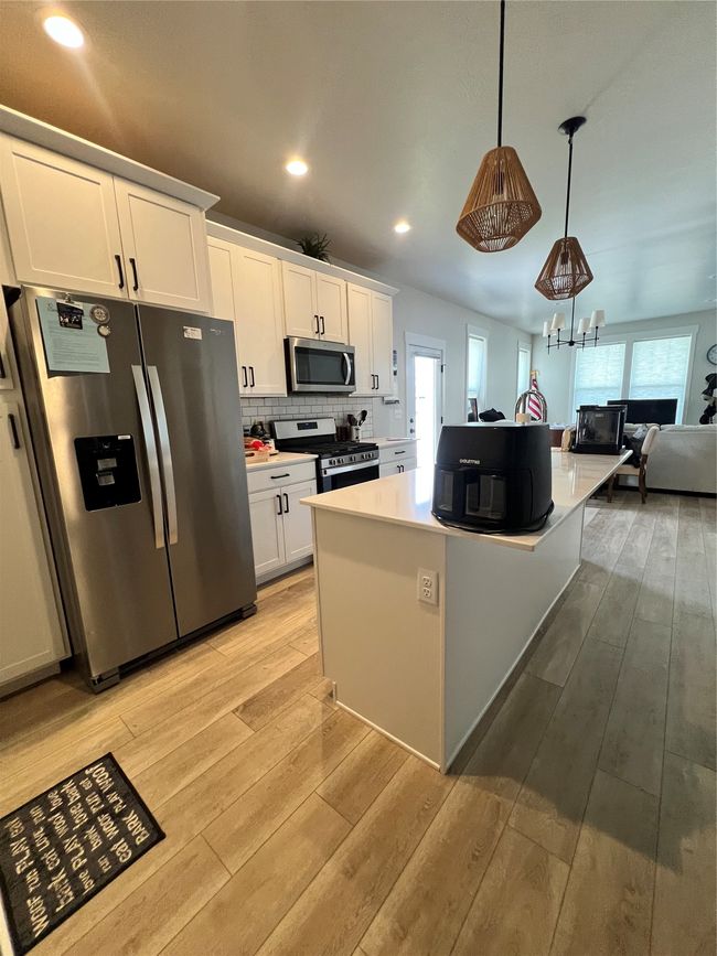 Kitchen featuring refrigerator, stainless steel gas stove, healthy amount of natural light, light wood-style flooring, and recessed lighting | Image 9