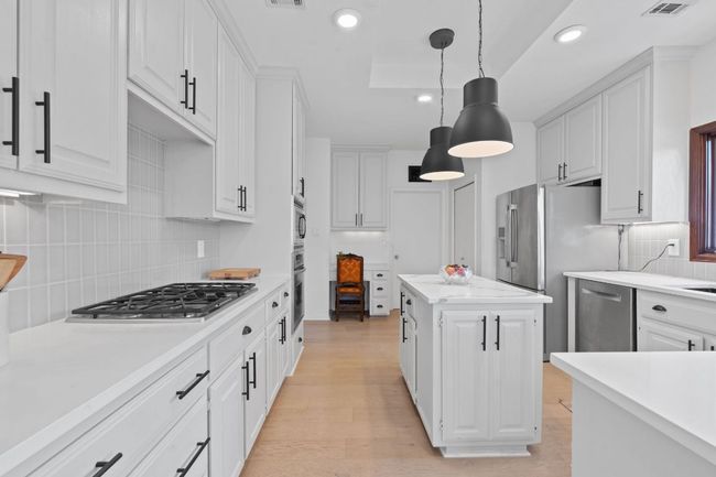 Kitchen featuring stainless steel appliances, light countertops, white cabinetry, and recessed lighting | Image 10