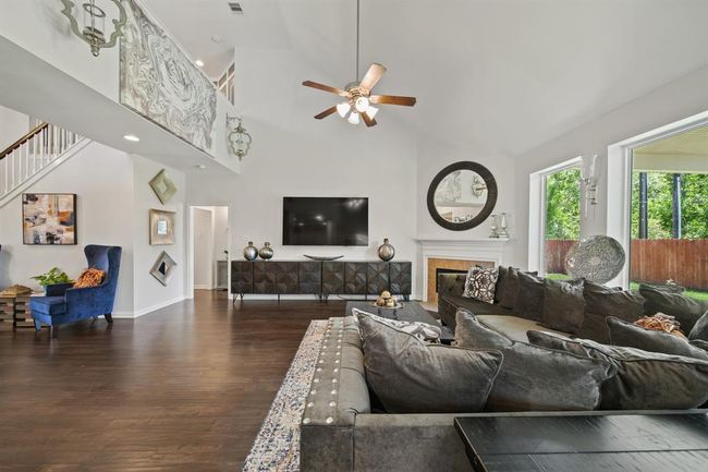 A view of the upstairs balcony, stylish lighting, and seamless flow into the other living areas highlight the thoughtful design and spacious layout of this beautiful family room. | Image 13