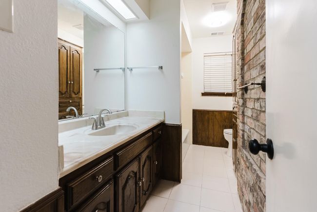 Bathroom featuring a wainscoted wall, visible vents, toilet, vanity, and a tub | Image 20