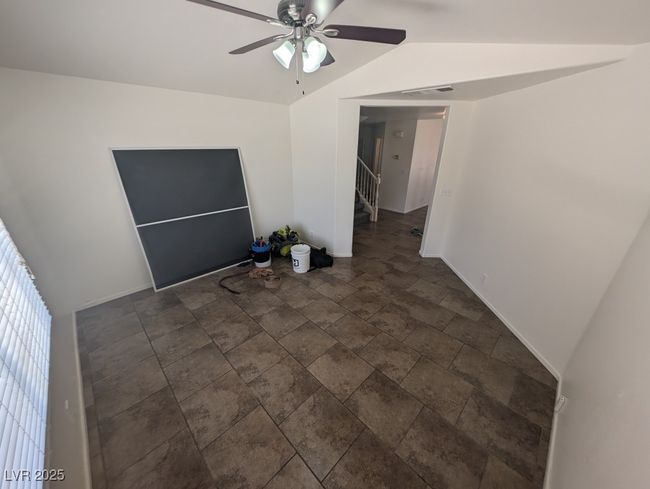 Spare room featuring lofted ceiling, stone finish flooring, baseboards, a ceiling fan, and stairs | Image 4