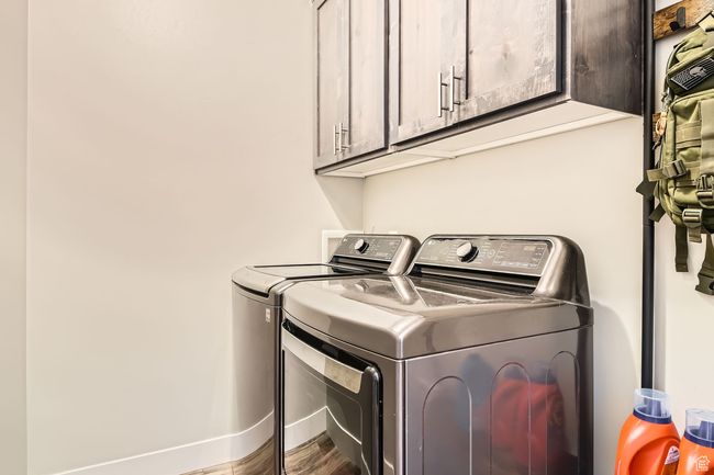 Laundry room featuring washing machine and clothes dryer, cabinet space, and wood finished floors | Image 19