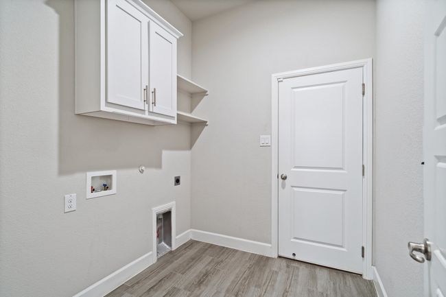Washroom with electric dryer hookup, cabinet space, hookup for a washing machine, and light wood-style floors | Image 22