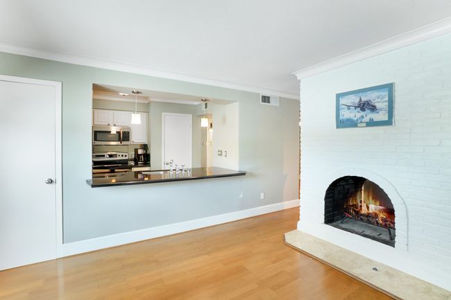 Unfurnished living room featuring ornamental molding, light wood finished floors, a brick fireplace, baseboards, and a sink | Image 5