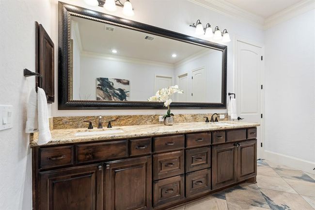 This spa-like Primary Bath is equipped with two undermount sinks, a granite countertop, a custom-framed mirror, and an abundance of built-in storage. | Image 30