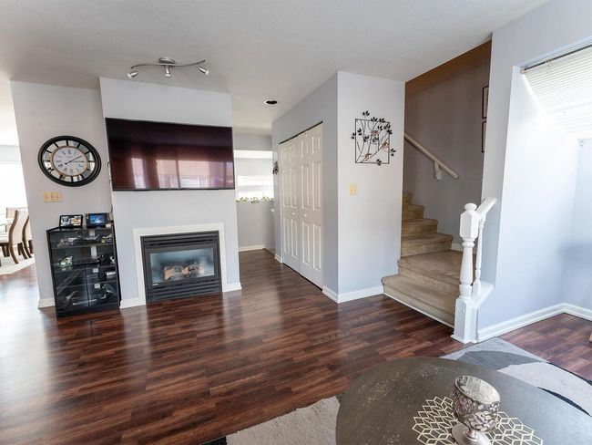 Living room with stairs, wood finished floors, baseboards, and a glass covered fireplace | Image 15