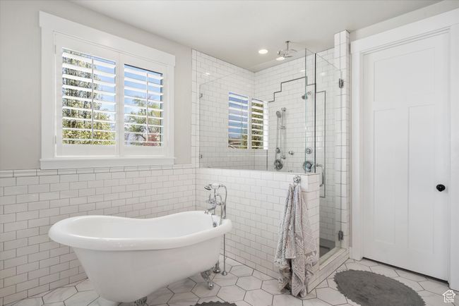 Bathroom featuring a soaking tub, tile walls, a shower stall, and tile patterned flooring | Image 26