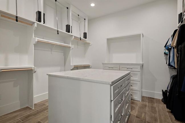 A generously sized walk-in closet featuring a central island and abundant storage space for effortless organization. | Image 31