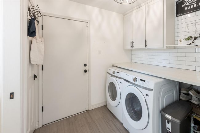 The laundry has built in cabinets, counter top space for laundry, and a half bath to the left side. The laundry room leads to the 3 car garage. | Image 40
