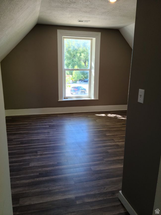 Bonus room with a textured ceiling, lofted ceiling, dark wood-type flooring, and baseboards | Image 27