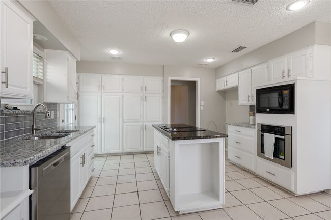 Kitchen with black appliances, light tile patterned floors, visible vents, and a sink | Image 16