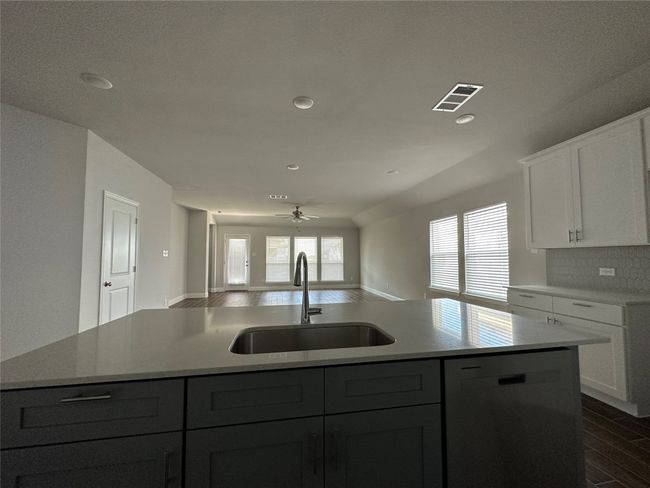 Kitchen featuring dishwashing machine, a kitchen island with sink, ceiling fan, light countertops, and dark wood-style flooring | Image 7