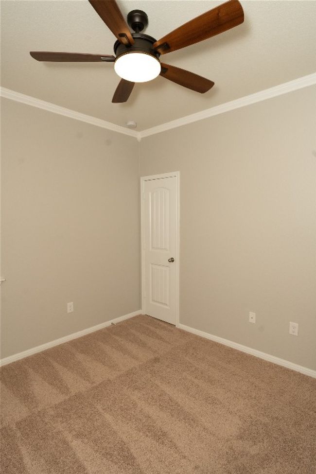 Empty room with light carpet, a ceiling fan, crown molding, and baseboards | Image 18