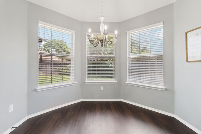 Unfurnished dining area featuring a chandelier, healthy amount of natural light, wood finished floors, and baseboards | Image 15