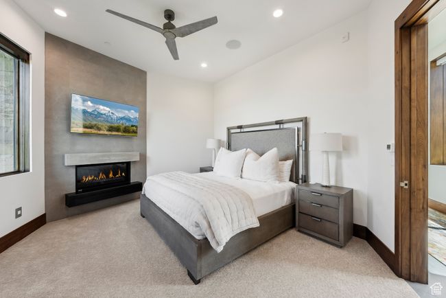 Bedroom with light carpet, a glass covered fireplace, recessed lighting, baseboards, and ceiling fan | Image 82