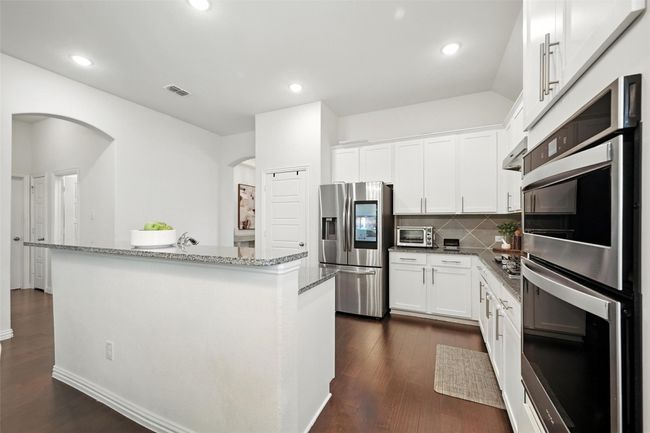 Kitchen with stainless steel appliances, decorative backsplash, stone countertops, dark wood finished floors, and recessed lighting | Image 10