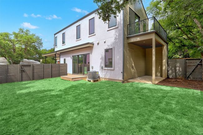 Back of property featuring a fenced backyard, a balcony, stucco siding, and a wooden deck | Image 24