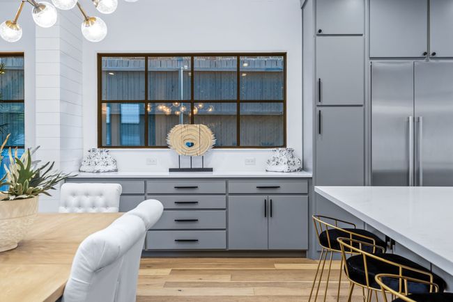 Kitchen with built in fridge, gray cabinets, light wood-type flooring, light countertops, and wooden walls | Image 10