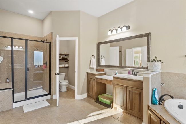 Full bath featuring a stall shower, toilet, tile patterned floors, vanity, and a bath | Image 24