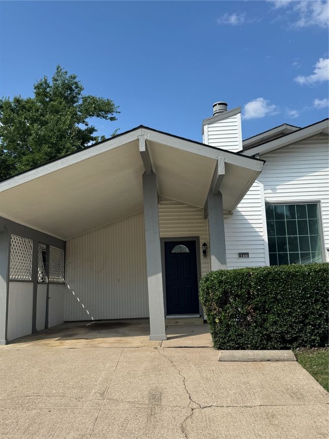 View of exterior entry featuring a chimney, a carport, and concrete driveway | Image 22