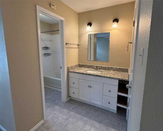 Bathroom featuring tile patterned floors, vanity, a textured ceiling, shower / washtub combination, and a textured wall | Image 14