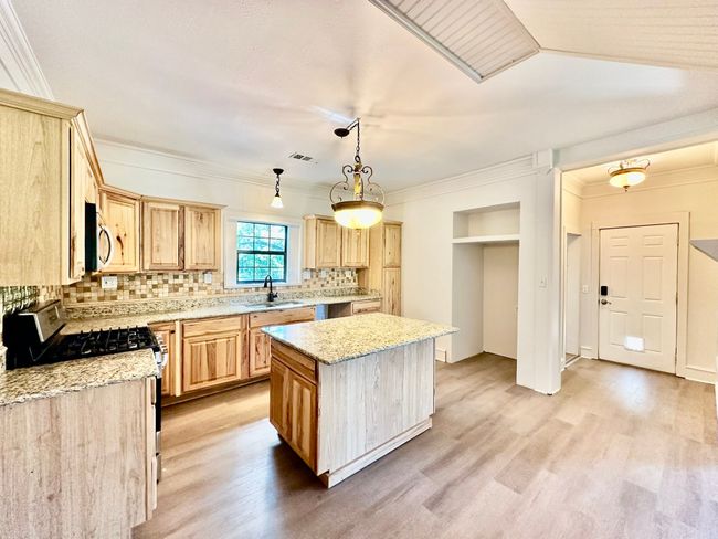 Kitchen with light brown cabinetry, appliances with stainless steel finishes, light wood-type flooring, and crown molding | Image 21