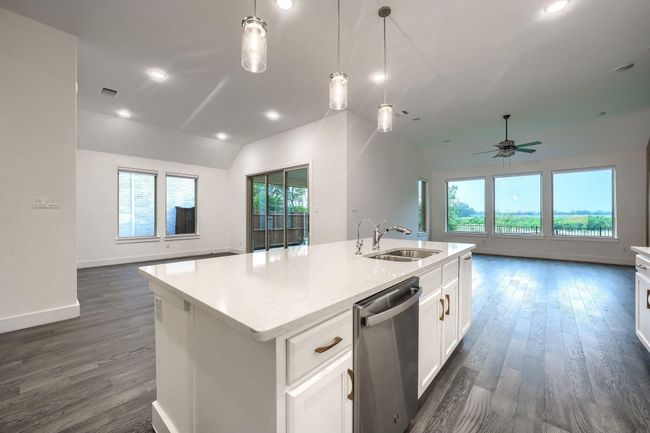 Kitchen featuring a sink, stainless steel dishwasher, open floor plan, lofted ceiling, and a kitchen island with sink | Image 12