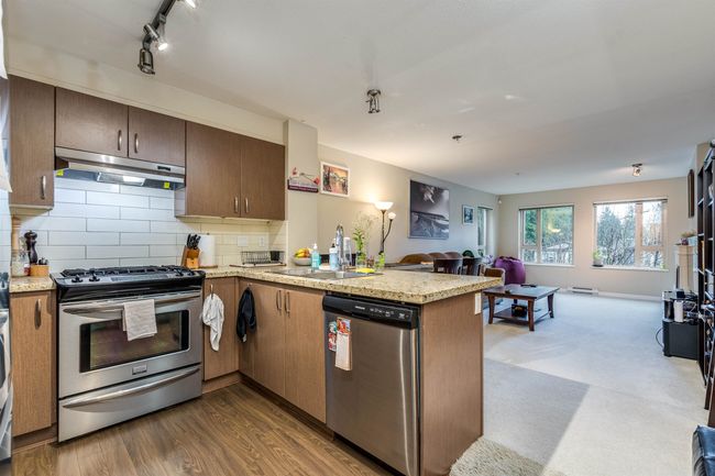 Kitchen with open floor plan, under cabinet range hood, a sink, a peninsula, and appliances with stainless steel finishes | Image 4