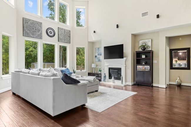 Living room with a towering ceiling, plenty of natural light, dark wood-type flooring, baseboards, and a glass covered fireplace | Image 6