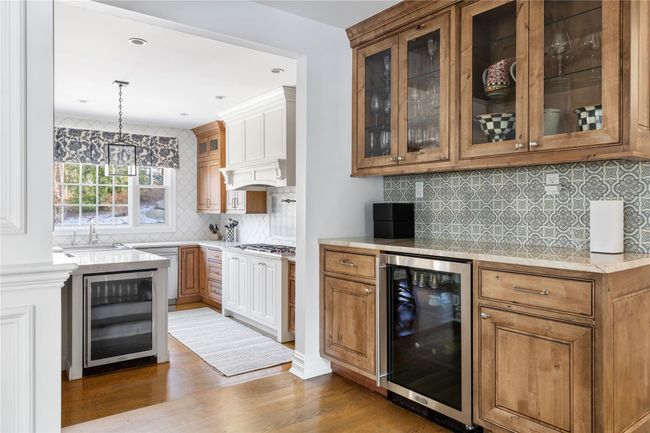 Bar featuring decorative backsplash, gas cooktop, a sink, and wine cooler | Image 20
