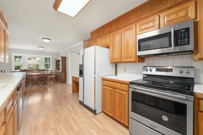 Kitchen featuring appliances with stainless steel finishes, light wood-style floors, light countertops, backsplash, and crown molding | Image 18