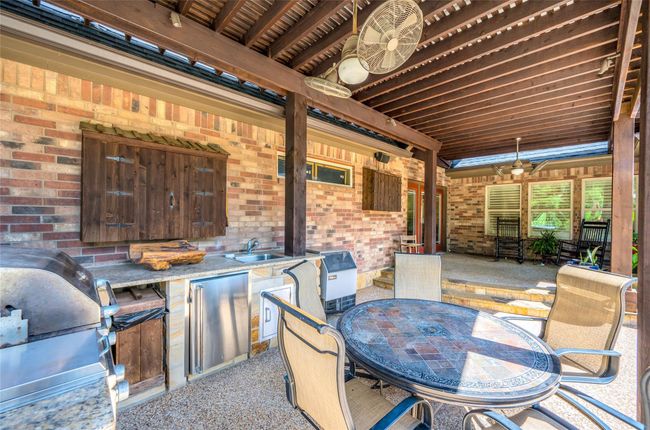 Spacious lower porch featuring a fully-equipped outdoor kitchen with double gas burners, a 3-burner grill with rotisserie and broiling options, plus an undercounter refrigerator. Ideal for entertaining! | Image 31
