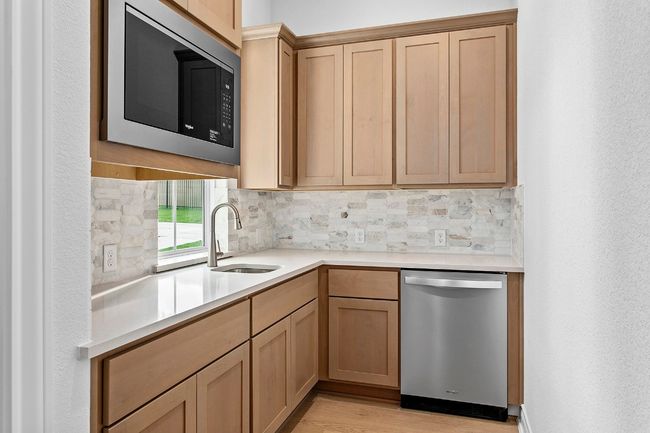 Kitchenette with dishwasher, built in microwave, tasteful backsplash, and light countertops | Image 19