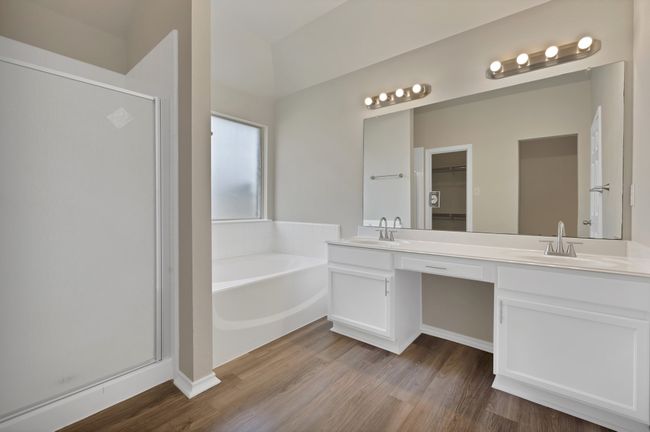 Bathroom featuring a stall shower, double vanity, a bath, wood finished floors, and a spacious closet | Image 14