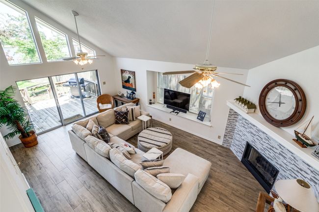 Living room with ceiling fan, a fireplace, wood finished floors, and high vaulted ceiling | Image 7