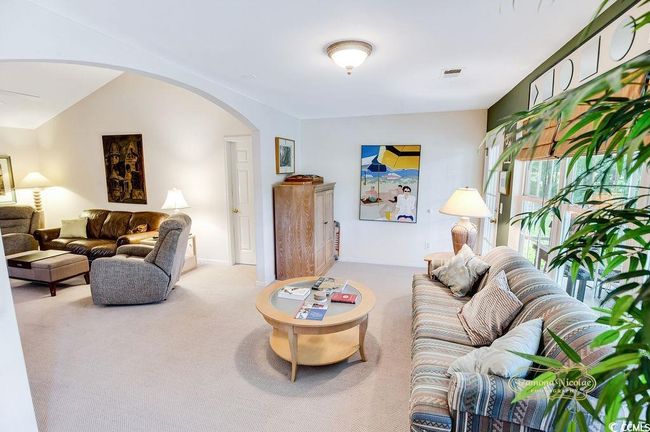 Living area with arched walkways and carpet flooring | Image 10