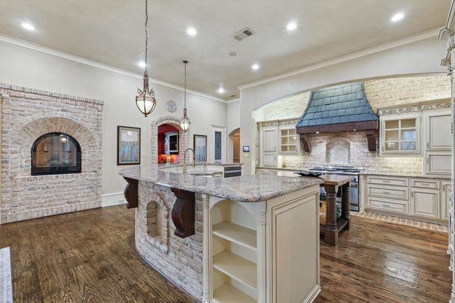 This elegant kitchen features 2 full size dishwashers, filtered water at the sink, a fireplace, a large walk-in pantry, a built in refrigerator, and a Thermador 6 burner gas range and double oven. | Image 16