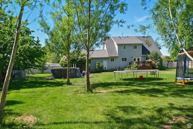 View of yard featuring a trampoline and a deck | Image 31
